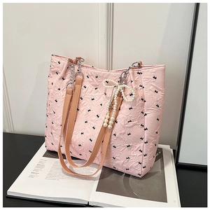 Detailed close-up of pink quilted tote bag with black bows and pearl charm accessory