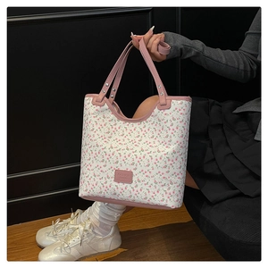 Close-up of pink floral tote bag with top handle and FASHION BAGS label on a model