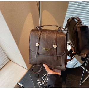 Détails de la texture en cuir PU marron et des deux boucles métalliques sur le sac à dos