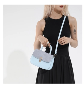 Vista detallada del bolso bandolera azul claro con textura gris y broche dorado