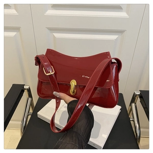 Close-up of bright red patent leather handbag with polished gold metal buckle detail