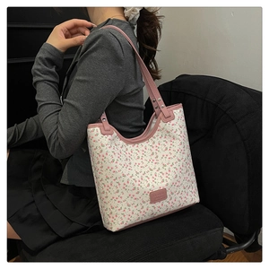 Detail of pink floral tote bag with studded shoulder strap on a sitting model