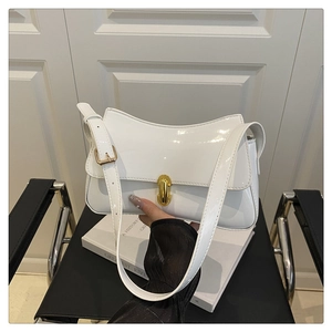 Detail of white patent leather shoulder bag with gold buckle and adjustable strap