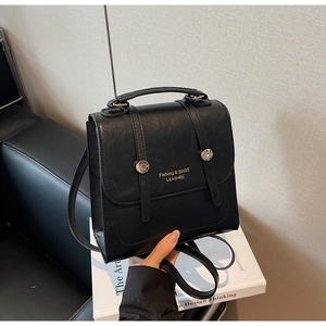 Vue détaillée de la texture en cuir PU noir mat et du lettrage doré sur le rabat du sac