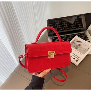 Macro shot of red crocodile texture handbag with gold metal lock in office setting