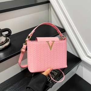 Sac bandoulière rose à texture tissée et logo V doré sur un fond minimaliste