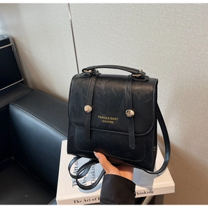 Detailed view of black PU leather backpack featuring gold metal buckles and top handle