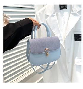 Detalle del bolso azul claro con textura de tela a rayas y cierre dorado