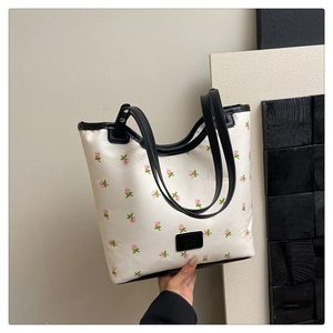 Close-up of a white tote bag featuring pink floral print and black leather trim details