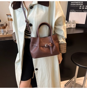 Détail du sac seau marron tressé avec bandoulière réglable et boucle décorative chic