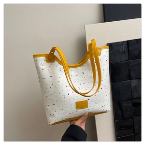 Detail of artistic splash ink pattern and yellow handle on cream tote bag