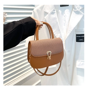 Detalle del bolso de silla marrón con solapa de textura tejida y hebilla de herradura dorada