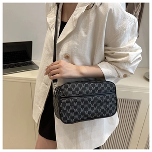 Détail du motif monogramme et de la bandoulière réglable en cuir du petit sac bandoulière