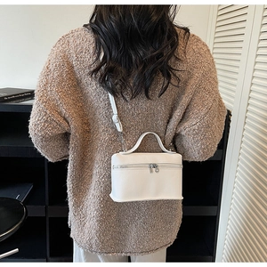 Détail du sac boîte en cuir blanc à motif litchi porté à l'épaule pour un style minimaliste