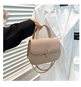 Detalle del bolso beige con solapa tejida, hebilla de herradura y metal dorado