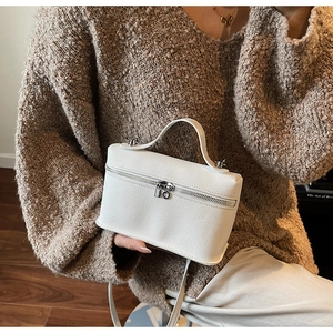 Detail of white box bag featuring litchi grain leather texture and metallic zipper