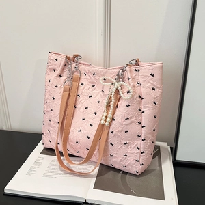 Pink quilted tote bag with black bows, leather chain straps, and pearl charm