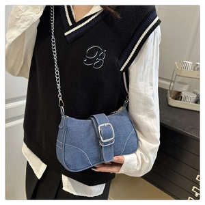 Detail of blue denim crossbody bag featuring silver chain strap and metal buckle