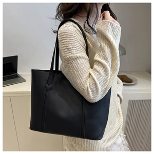 Close-up of black leather tote bag with V-shaped stitching and matte texture details