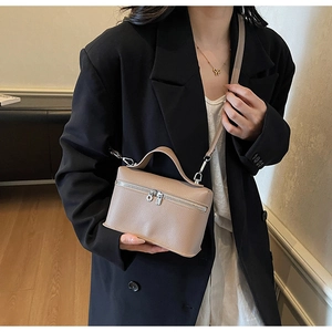 Detail of the litchi texture leather surface and dual metal zippers on this crossbody bag