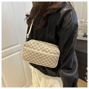 Sac bandoulière avec motifs de lettres grises et sangle ajustable sur une veste en cuir noir