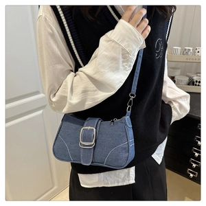 Detail of blue denim vintage underarm bag with silver buckle and white stitching