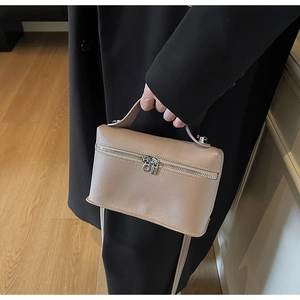 Close-up of beige lychee leather crossbody bag with dual silver zippers and top handle