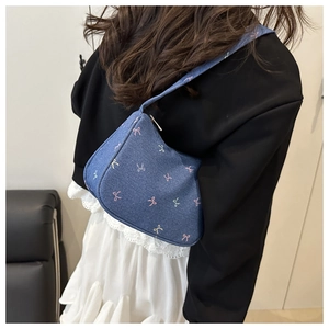 Detail of blue denim shoulder bag with colorful mini bows shown from a side-view angle
