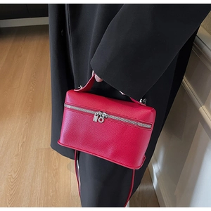 Detail of red lychee grain leather handbag with silver hardware and zipper closure