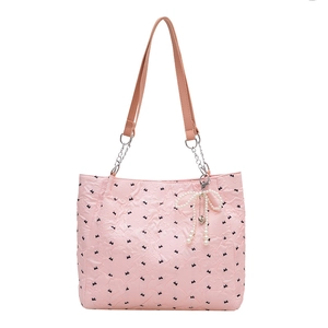 Pink quilted tote bag with black bow patterns and elegant pearl pendant detail