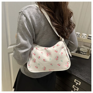 Gros plan d'un sac porté épaule blanc à fleurs roses et nœuds porté par un mannequin