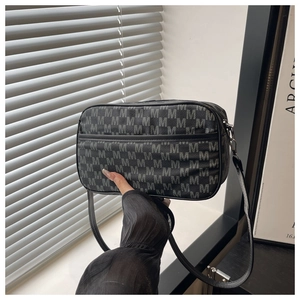 Close-up of black square crossbody bag with all-over M-letter print and zipper closure