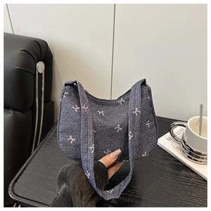 Detail of grey denim shoulder bag featuring pink bow patterns and dual strap design