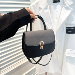 Elegante bolso patchwork negro y gris con hebilla de herradura dorada en traje blanco