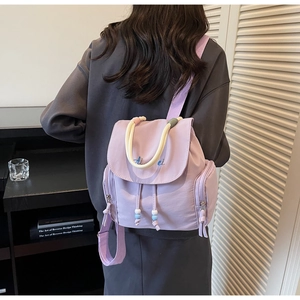 Lifestyle shot of a lavender fabric backpack with rope handles and side pockets indoors