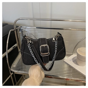 Detail of black denim baguette bag featuring white contrast stitching and silver metal buckle