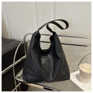 Détail de la texture tissée noire d'un grand sac cabas avec bandoulière large
