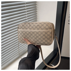 Detail view of beige crossbody bag with M-pattern monogram and adjustable strap