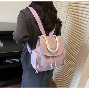 Detail of purple nylon backpack with white woven handle and embroidered brand logo