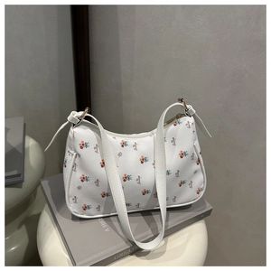 Détail du sac blanc avec imprimés floraux et cursifs posé sur un livre minimaliste