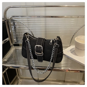 Detail of black denim shoulder bag with bold silver hardware and chain on acrylic shelf