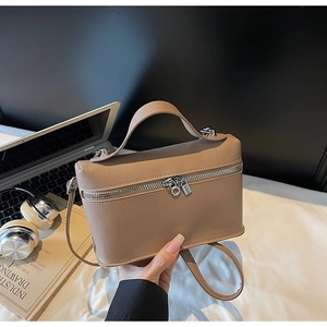 Close-up of khaki lychee leather handbag with silver zippers and a top handle