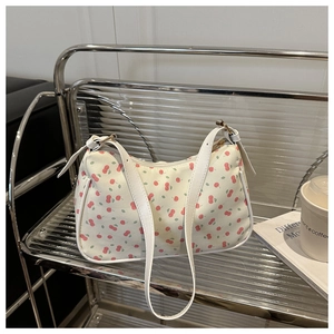 Détail du sac à bandoulière blanc imprimé cerises avec fermeture éclair sur étagère