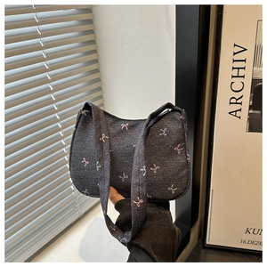 Close-up of gray denim shoulder bag featuring cute colorful bow embroidery and zipper