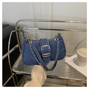Detail of blue denim shoulder bag with white stitching, silver buckle and metal chain strap