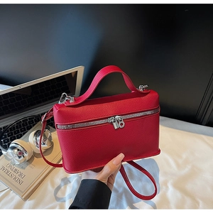 Top view of red grained leather box bag with silver zippers and commute accessories