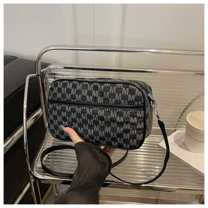 Détail de sac bandoulière avec imprimé lettres M et fine bandoulière en cuir noir