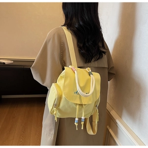 Detail des gelben Nylon-Rucksacks mit weißem Seilgriff und bunter Perlen-Kordelzug