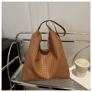 Détail macro du sac hobo en cuir tressé marron caramel avec texture intrecciato