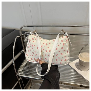 Détail du sac à bandoulière crème avec motifs cerises roses et bandoulière en similicuir